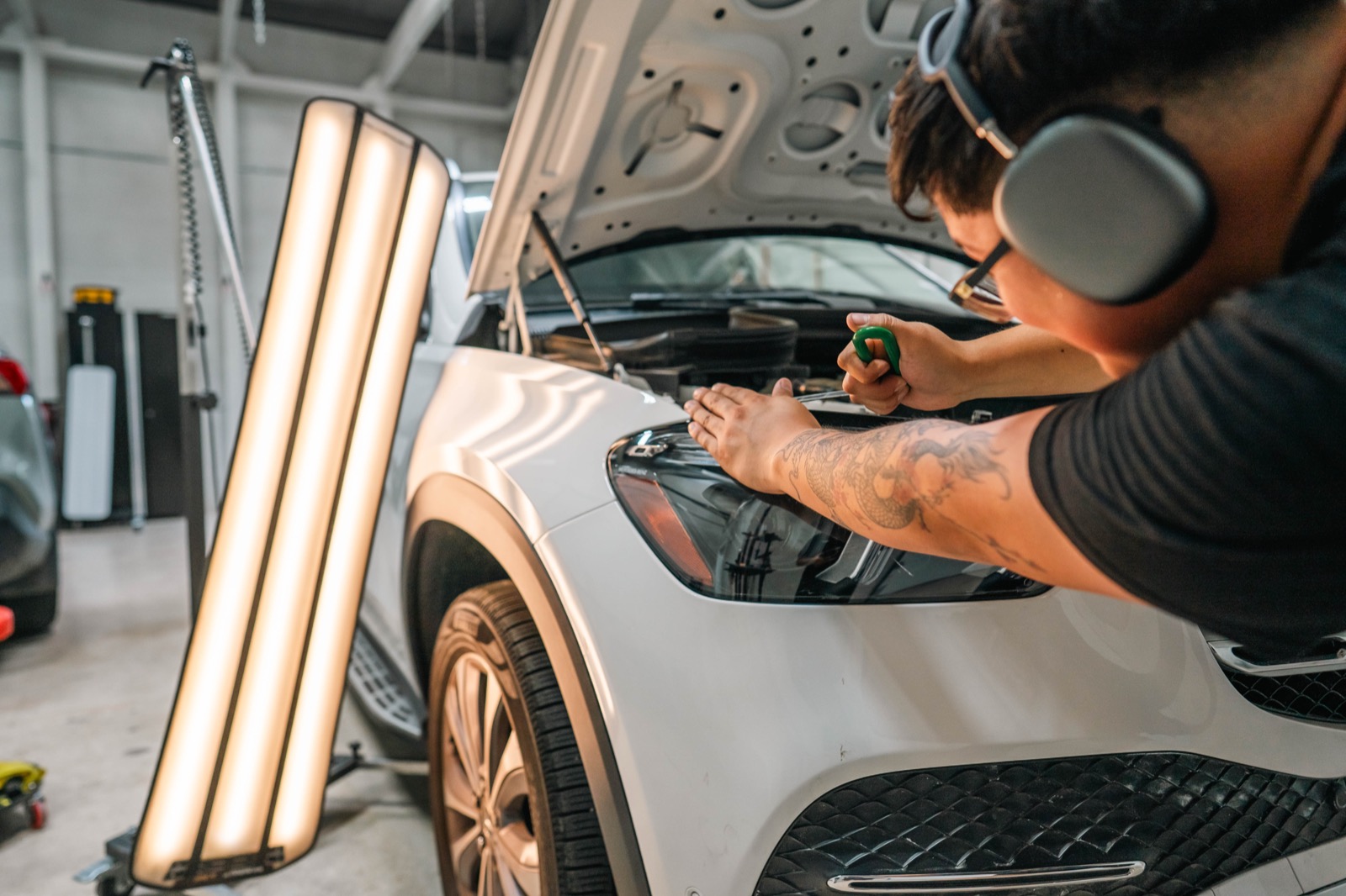 AHT technician pulling a hail dent on a white Mercedes with reading lights